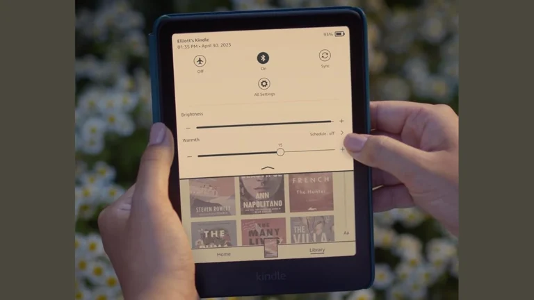 Kindle Colorsoft in a teal cover held in two hands, showing the quick settings panel with the Brightness slider and the Warmth slider set to 15
